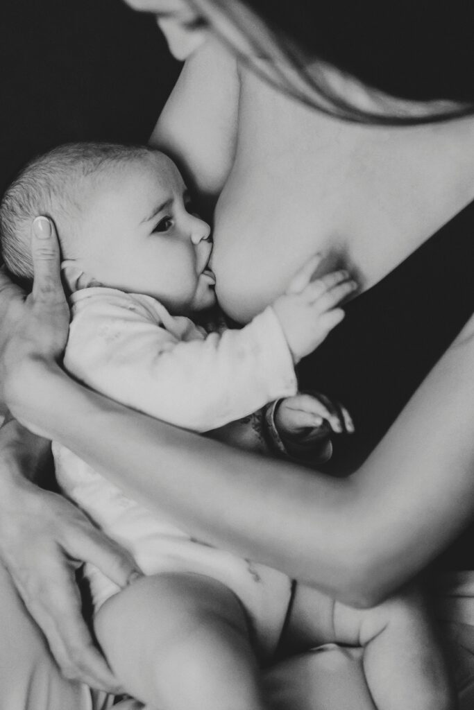 Tender black and white portrait of a mother breastfeeding her baby, showcasing motherhood and care.